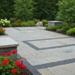 Landscaped patio featuring stone pavers with decorative borders, surrounded by vibrant flowers and greenery, illustrating aesthetic appeal for landscaping projects in Hot Springs.